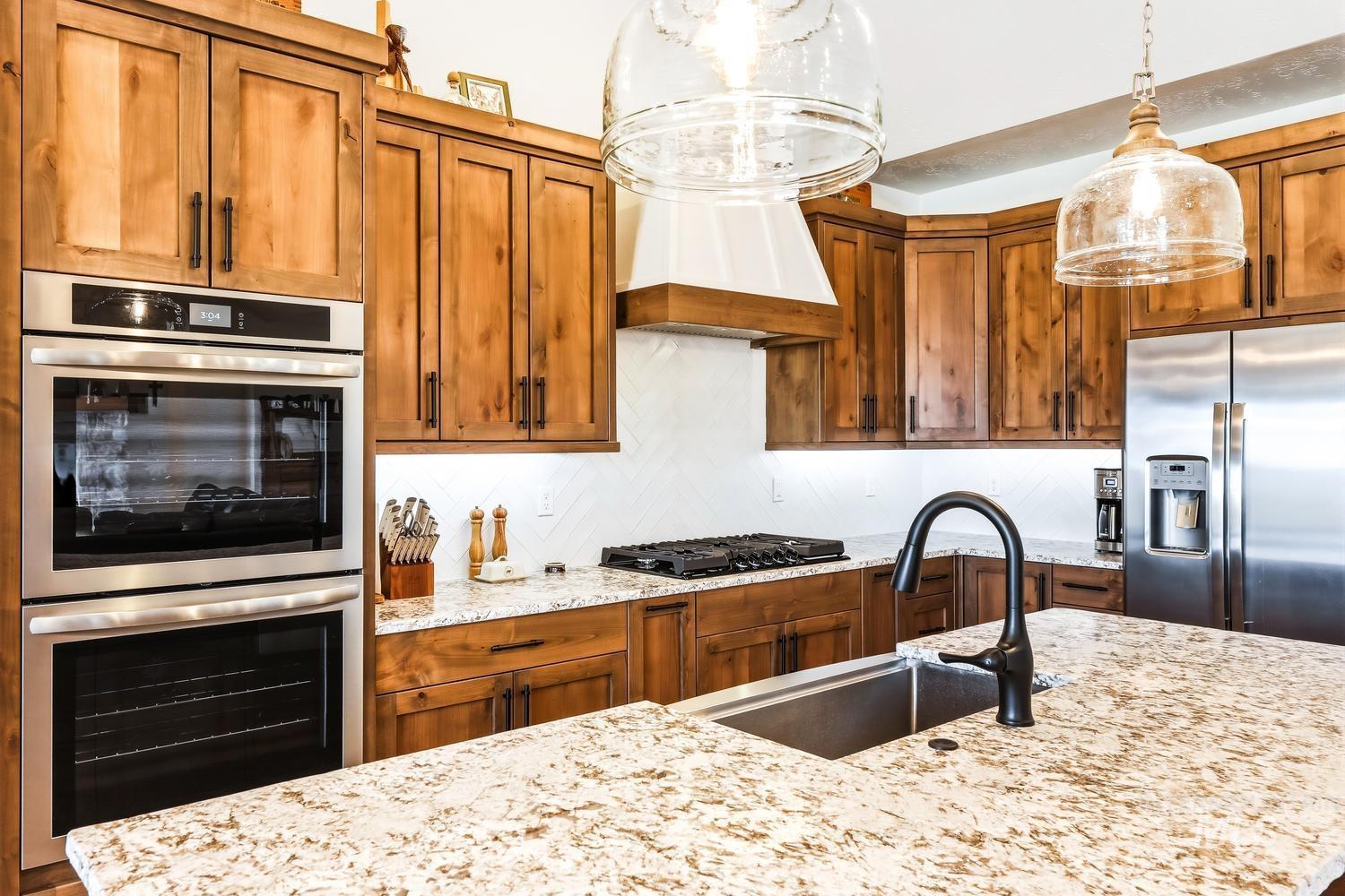 18658 Tranquil Place Caldwell, ID 83607 - Photo 12 of 44 Spacious kitchen featuring warm wood cabinetry, granite countertops, and stainless steel appliances including a built-in double oven and side-by-side refrigerator