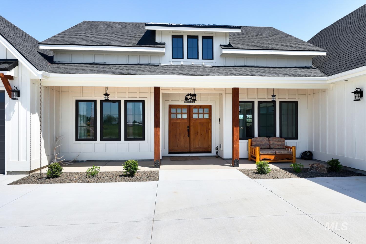 18658 Tranquil Place Caldwell, ID 83607 - Photo 2 of 44 Modern farmhouse exterior with white board and batten siding, a dark asphalt shingle roof, and a prominent front porch