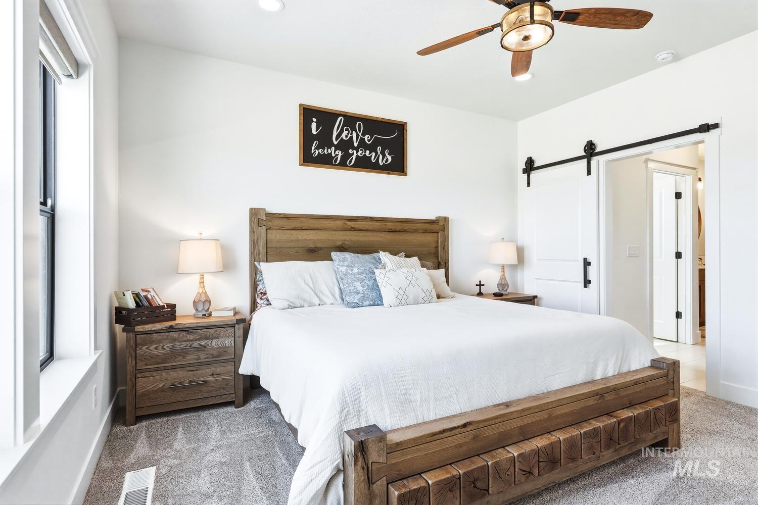 18658 Tranquil Place Caldwell, ID 83607 - Photo 21 of 44 Spacious bedroom featuring light-toned walls, gray carpeting, a window with white trim, and a ceiling fan with integrated lighting
