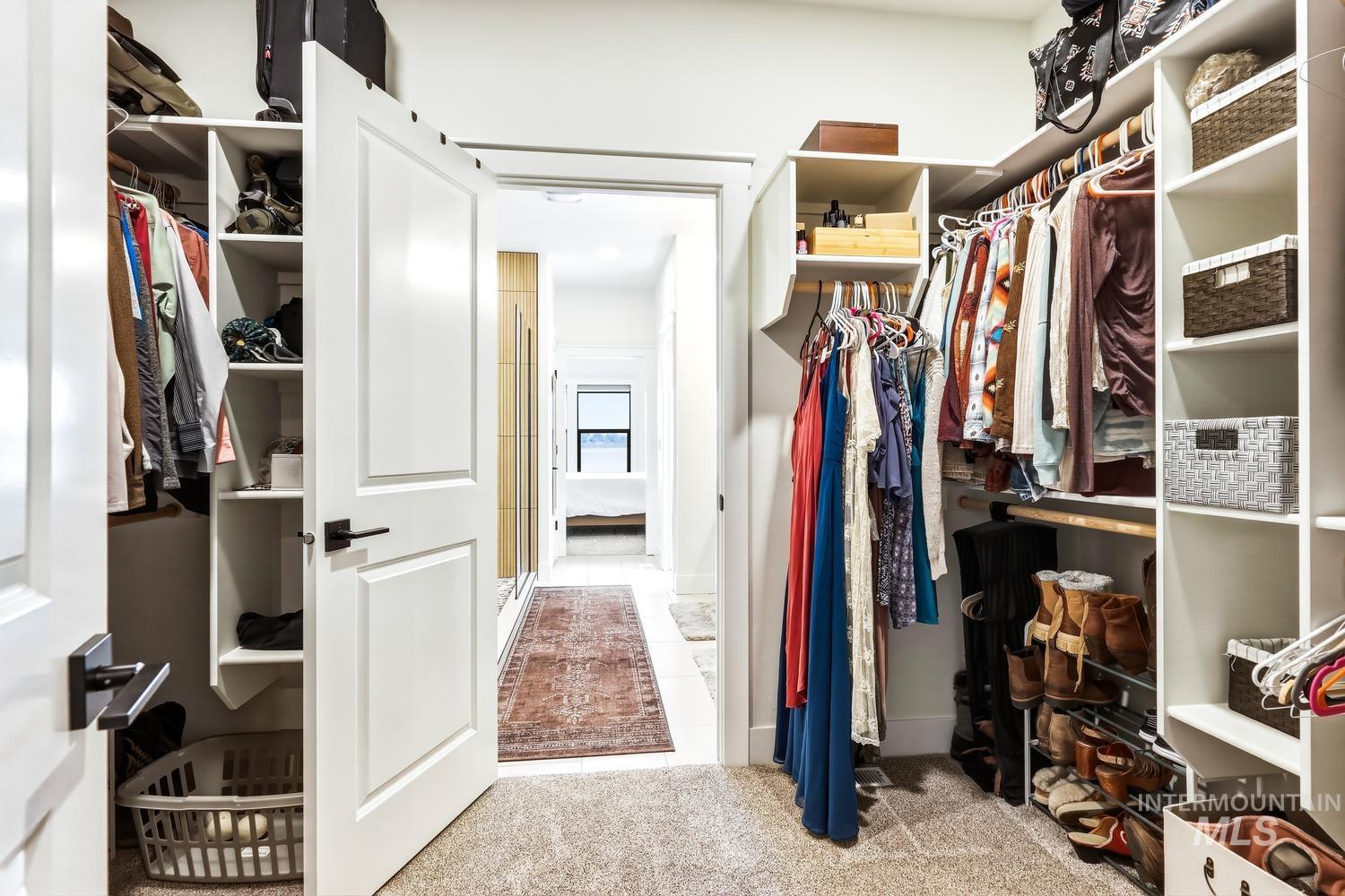 18658 Tranquil Place Caldwell, ID 83607 - Photo 27 of 44 Walk-in closet featuring extensive built-in shelving, multiple hanging rods, carpet flooring, and a clear sightline into an interior hallway