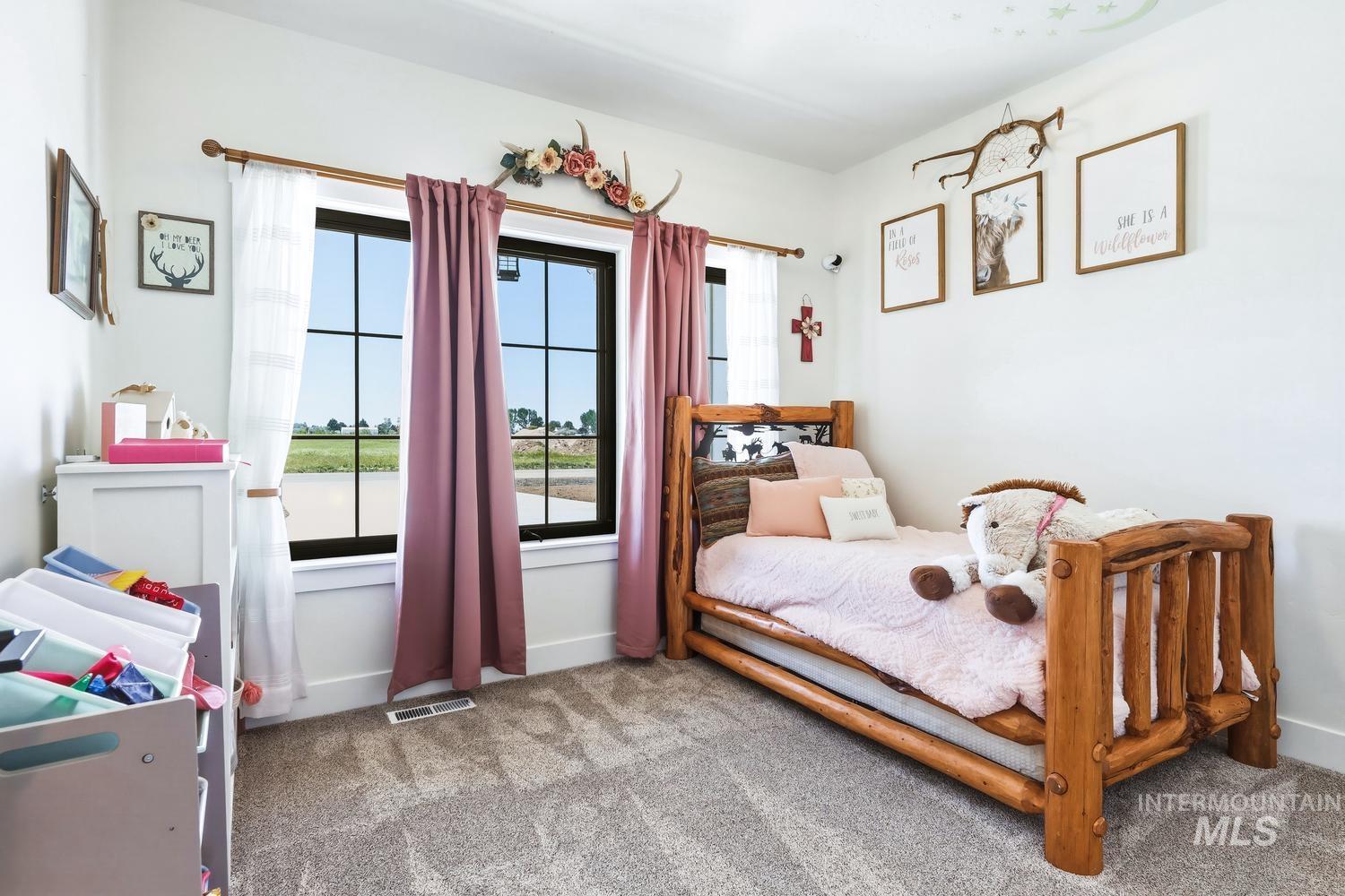 18658 Tranquil Place Caldwell, ID 83607 - Photo 28 of 44 Carpeted room featuring a large window, white walls, and a rustic wood-frame bed