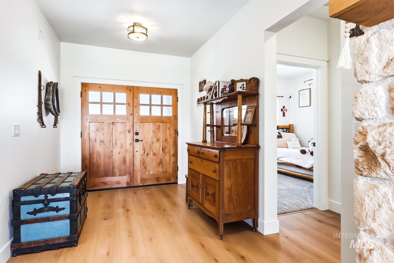 18658 Tranquil Place Caldwell, ID 83607 - Photo 3 of 44 Entryway featuring natural wood double doors with divided lites, light wood-finish flooring, a neutral ceiling-mounted light fixture, and white painted walls