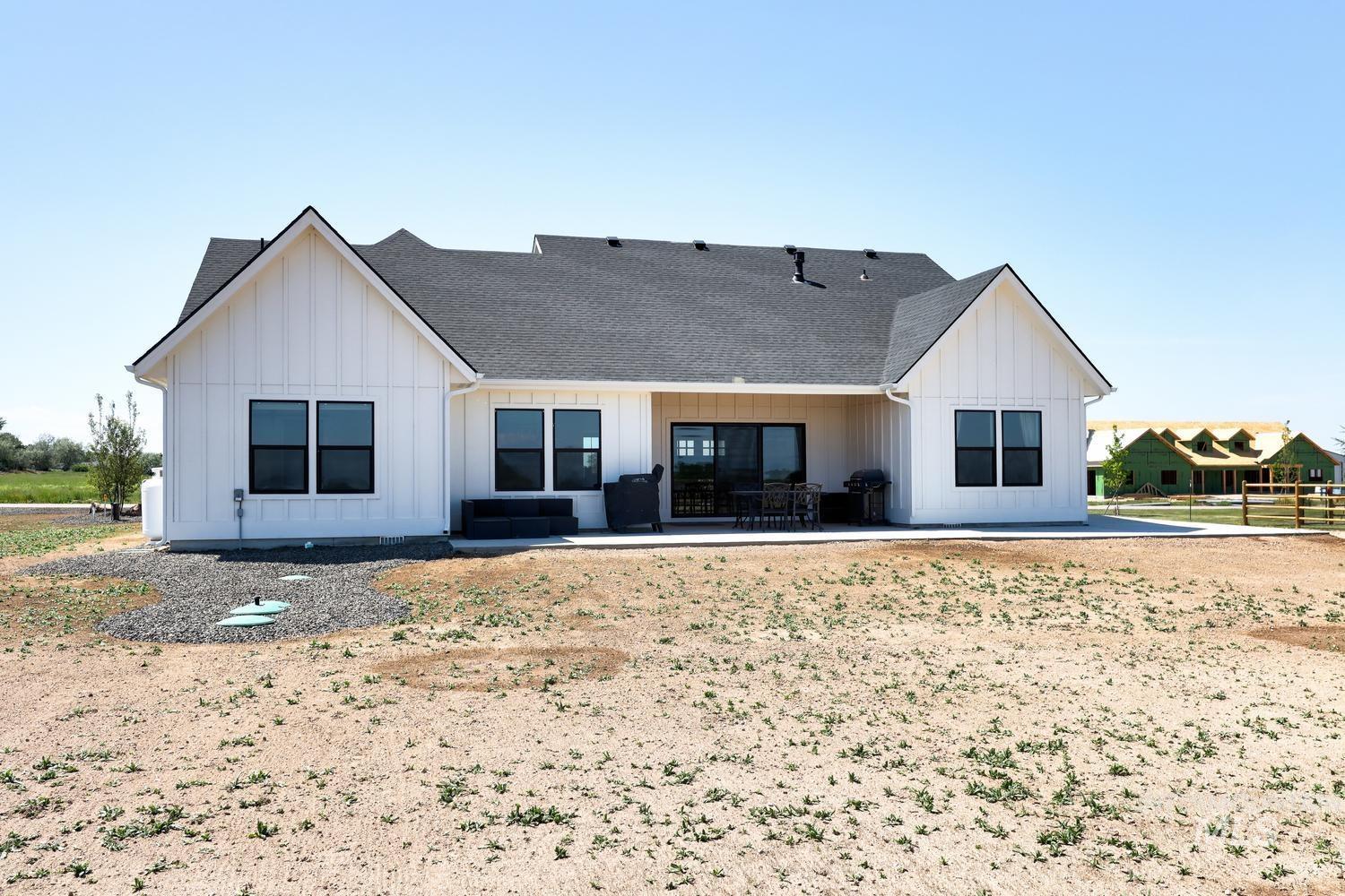 18658 Tranquil Place Caldwell, ID 83607 - Photo 42 of 44 Rear exterior featuring white board and batten siding, black-framed windows, and a covered patio area