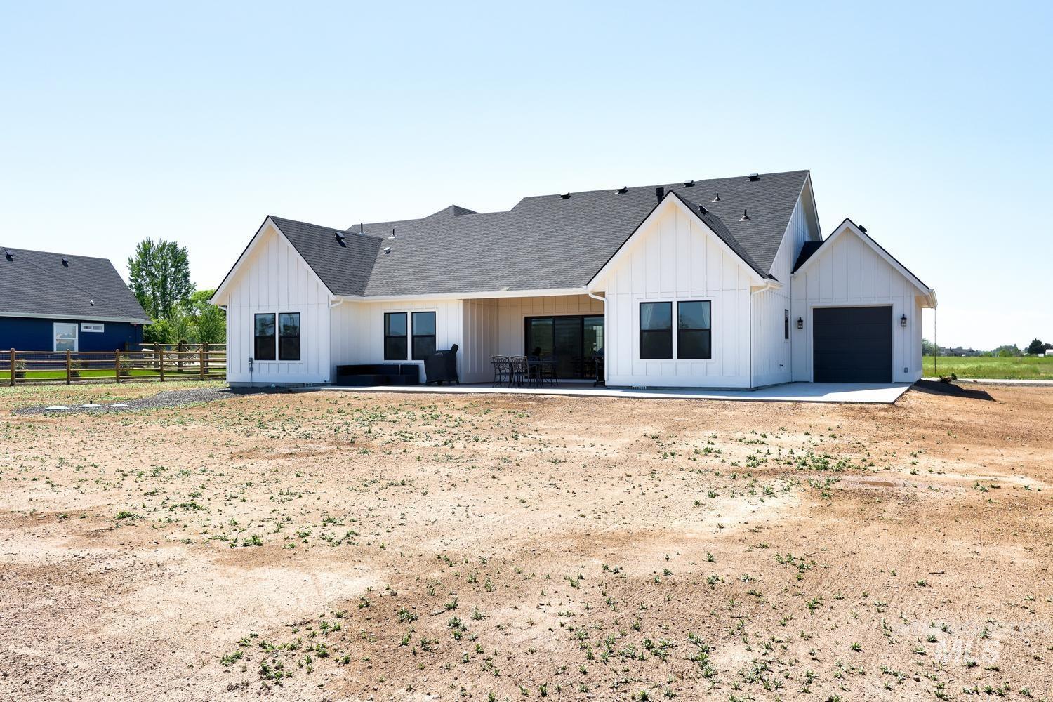 18658 Tranquil Place Caldwell, ID 83607 - Photo 43 of 44 Rear exterior of a single-story home featuring board and batten siding, a dark shingle roof, and a covered patio area