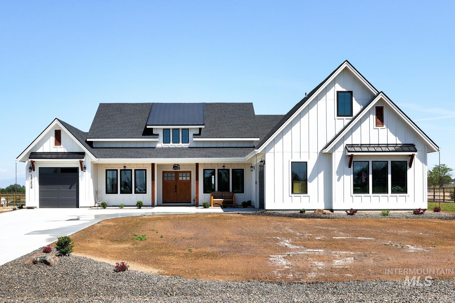 18658 Tranquil Place Caldwell, ID 83607 - Photo 44 of 44 Modern farmhouse exterior with white board and batten siding, a dark asphalt shingle roof, and a prominent metal roof dormer