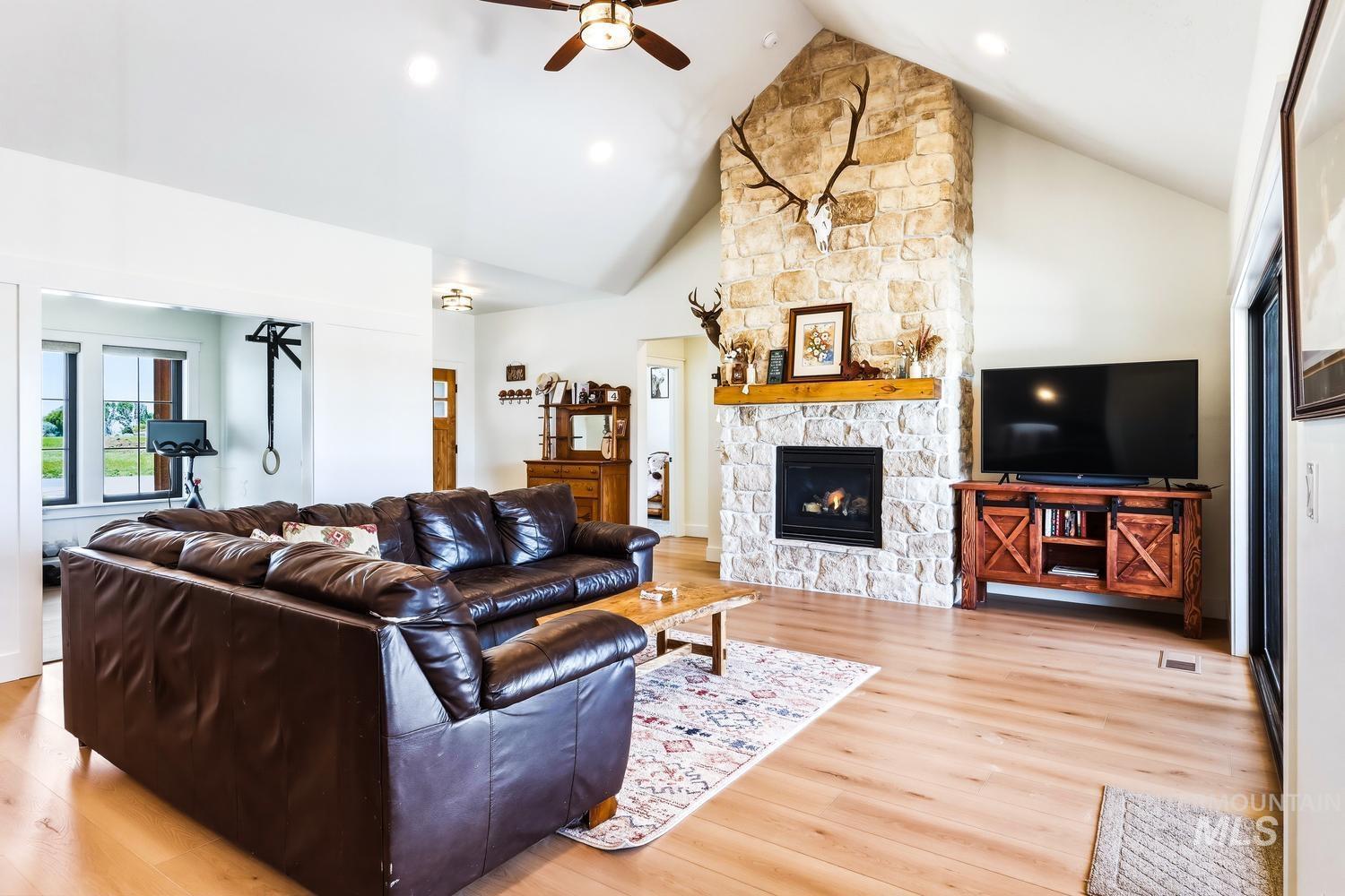 18658 Tranquil Place Caldwell, ID 83607 - Photo 7 of 44 Vaulted ceiling living area featuring a stone fireplace with wood mantel, wood-finish flooring, and recessed lighting
