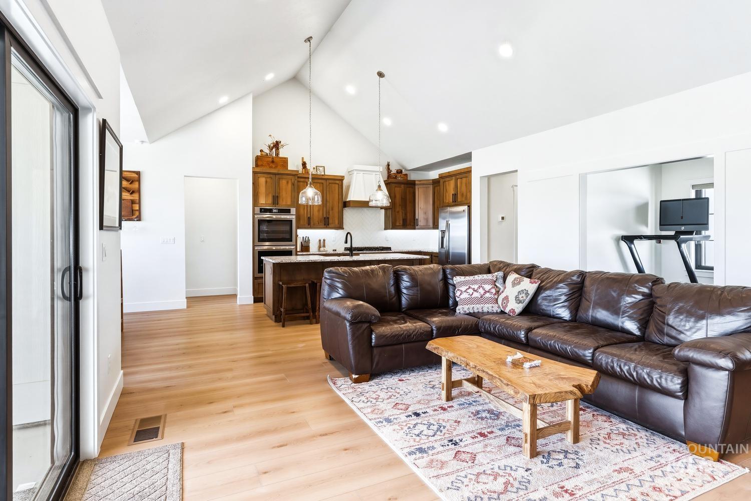 18658 Tranquil Place Caldwell, ID 83607 - Photo 9 of 44 Open-concept living area featuring vaulted ceilings, light wood-finish flooring, recessed lighting, and a modern kitchen with wood cabinetry and stainless steel appliances