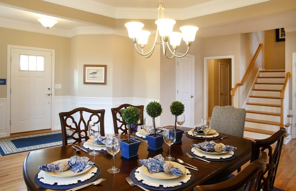 a dining room with wooden floor a chandelier a wooden table and chairs