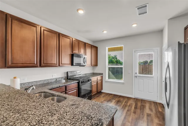 a kitchen with stainless steel appliances granite countertop a refrigerator a stove top oven a sink and dishwasher