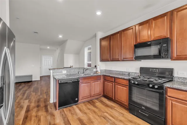 a kitchen with stainless steel appliances granite countertop wooden cabinets granite counter tops and a hard wood floors