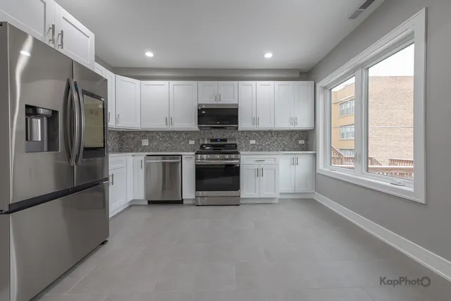 a kitchen with stainless steel appliances granite countertop a refrigerator a stove a sink and a microwave