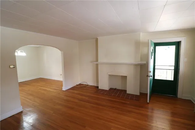 an empty room with wooden floor fireplace and windows