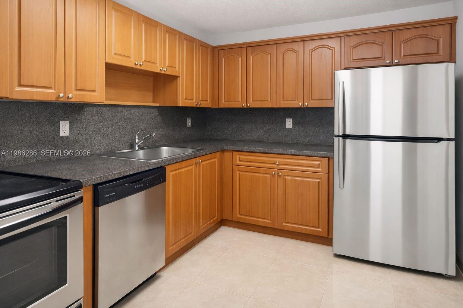 15620 Southwest 80th Street, Unit H304 Miami, FL 33193 - Photo 2 of 8 a kitchen with stainless steel appliances granite countertop a refrigerator sink and cabinets