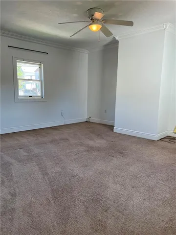 an empty room with a fan & windows