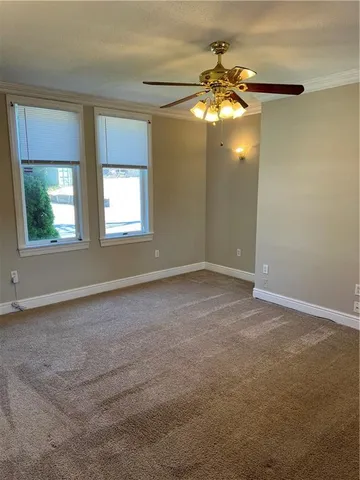 an empty room that has a chandelier fan and windows