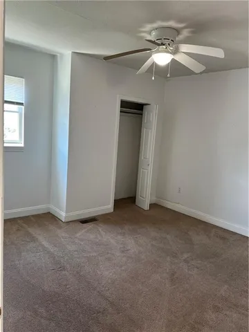an empty room with a chandelier fan and windows