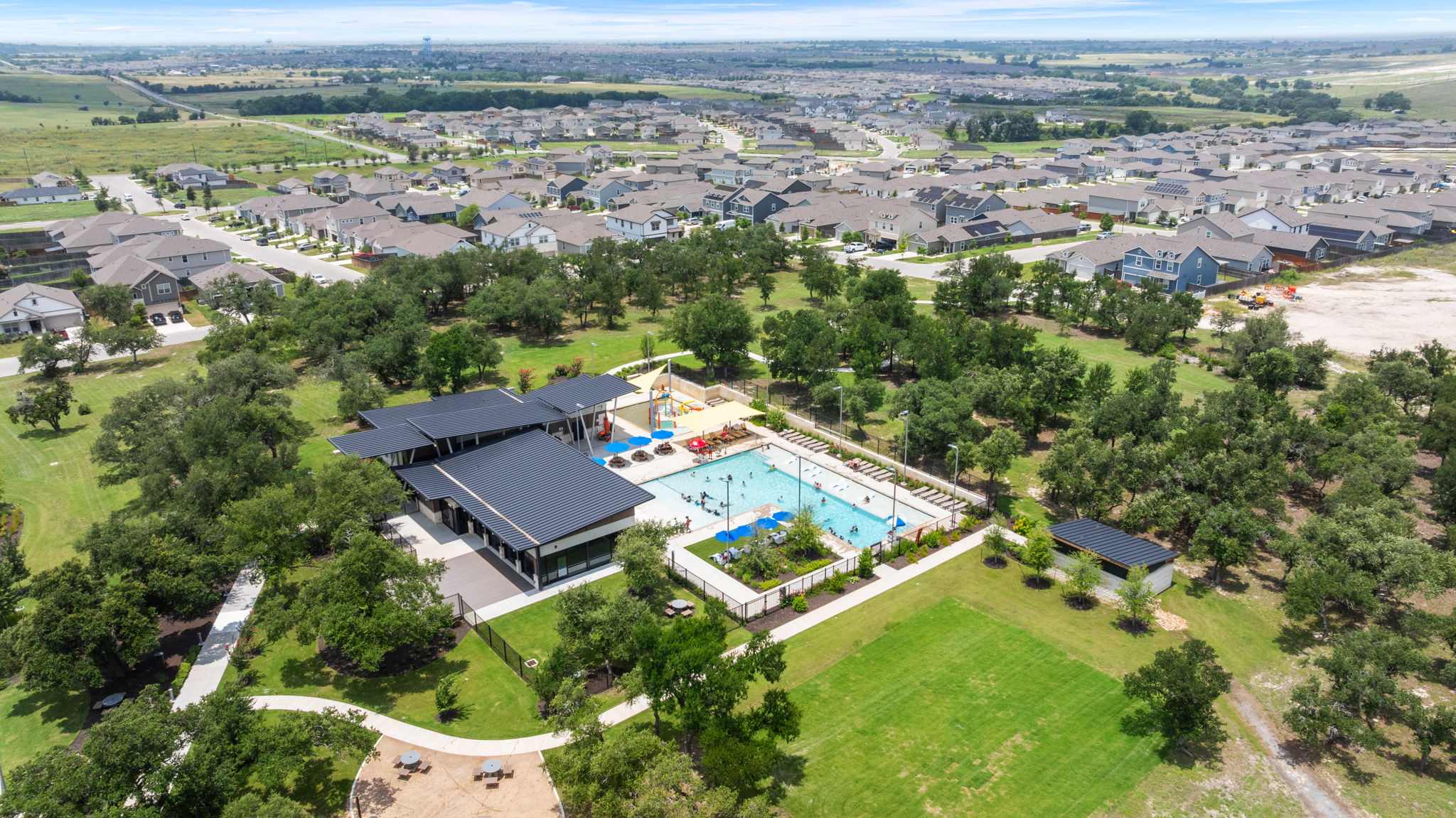 313 Mclintock Road Jarrell, TX 76537 - Photo 36 of 40 An aerial perspective reveals a vibrant community with a refreshing swimming pool at its core, surrounded by verdant parkland.