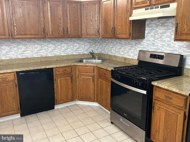 a kitchen with granite countertop a stove top oven microwave and cabinets