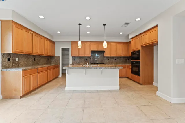 a large kitchen with a large counter top stainless steel appliances and cabinets