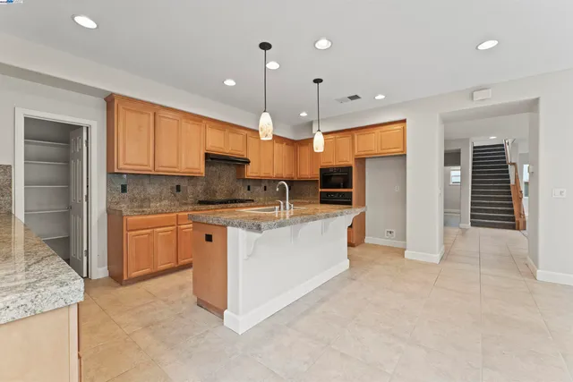a large kitchen with stainless steel appliances granite countertop a stove a sink and a refrigerator