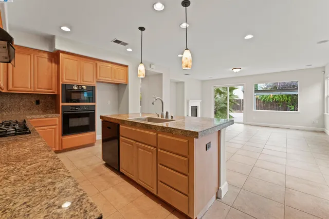 a kitchen with stainless steel appliances granite countertop a stove a sink a oven and a refrigerator with wooden floor