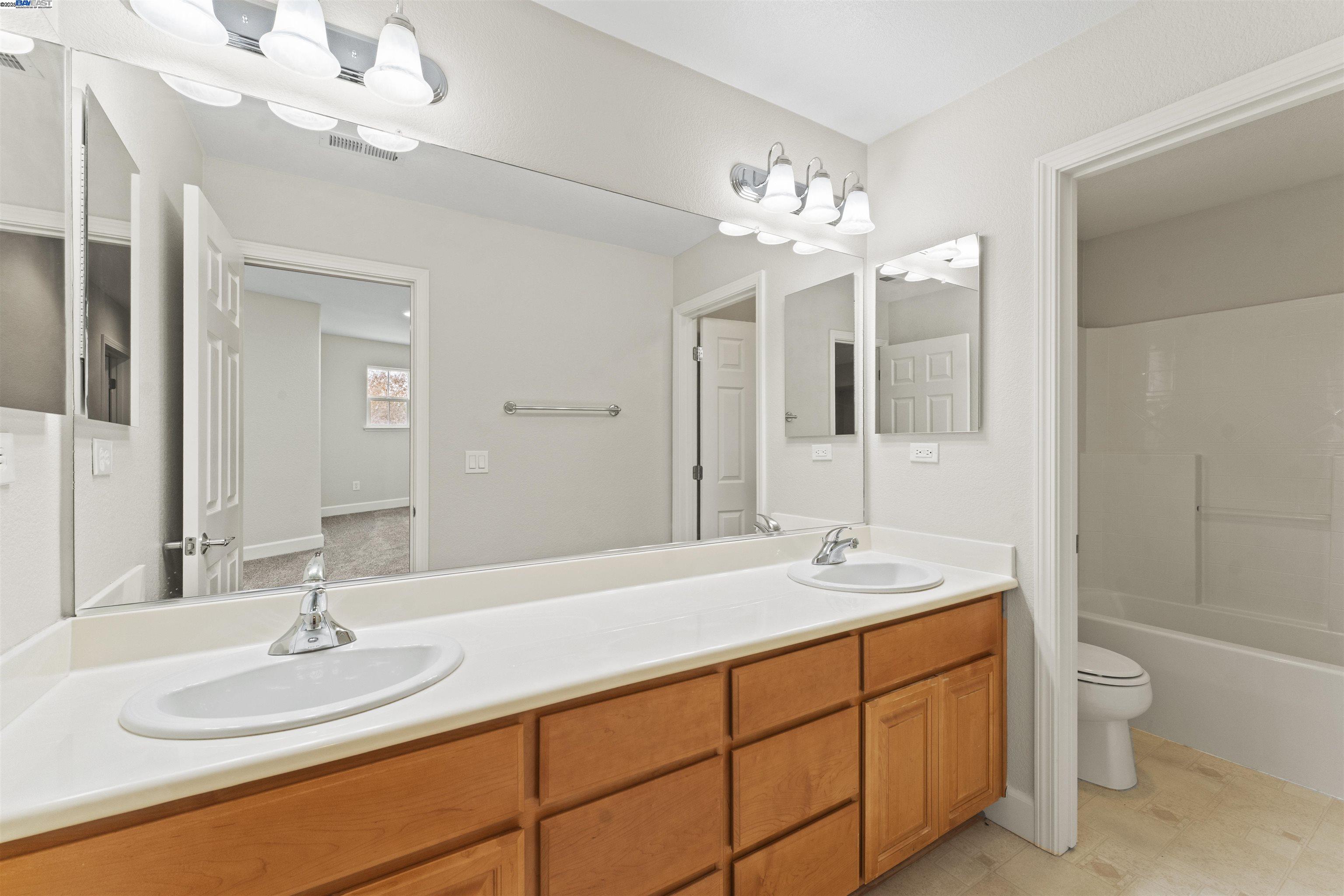 204 Daylilly Lane Patterson, CA 95363 - Photo 28 of 52 a bathroom with a sink double vanity granite tub and a mirror