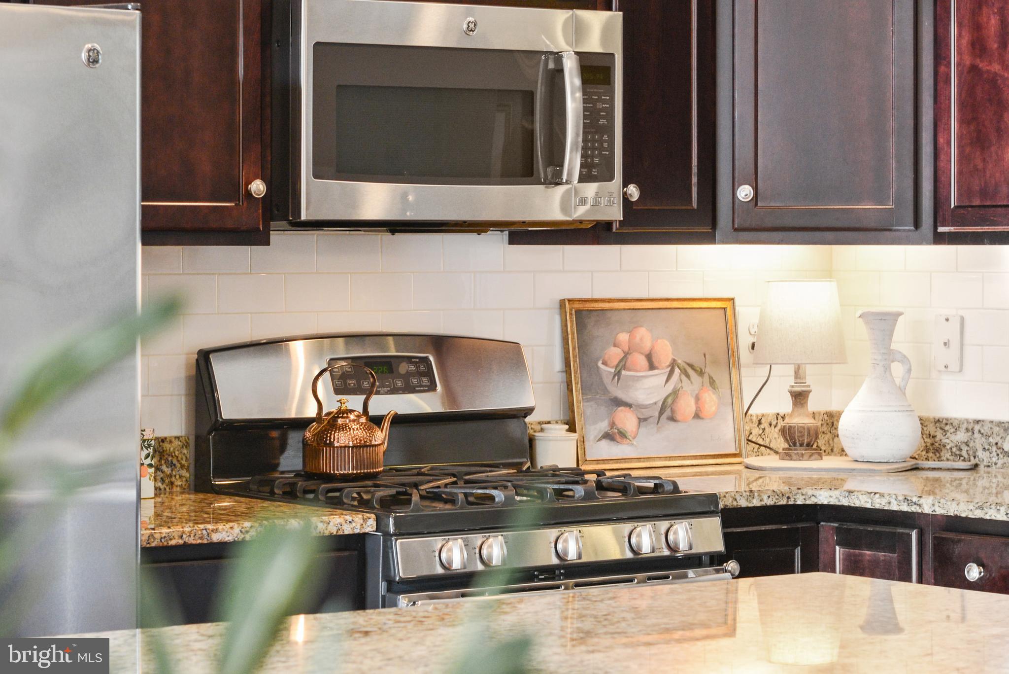 2709 Osprey Way North Frederick, MD 21701 - Photo 4 of 64 a kitchen with stainless steel appliances granite countertop a stove a microwave and wooden cabinets