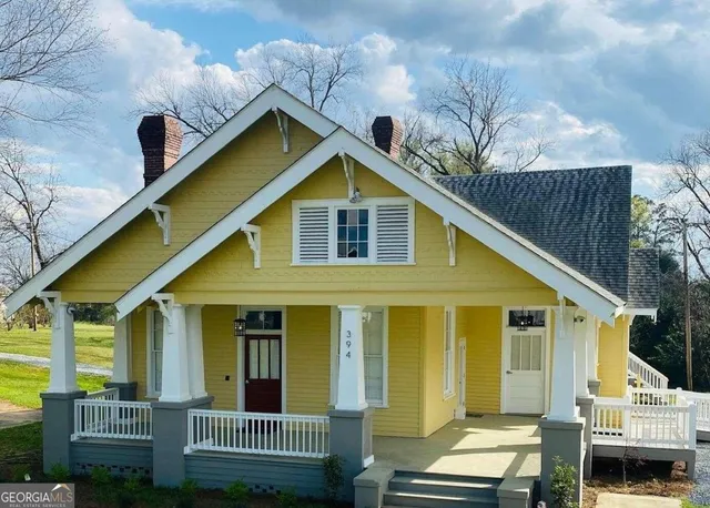 a view of a house with wooden fence and large trees