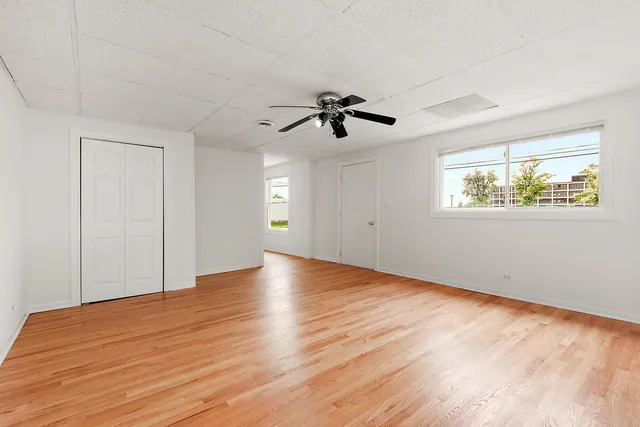 a view of empty room with wooden floor and fan