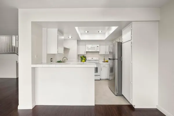 a kitchen with a refrigerator a sink and white cabinets