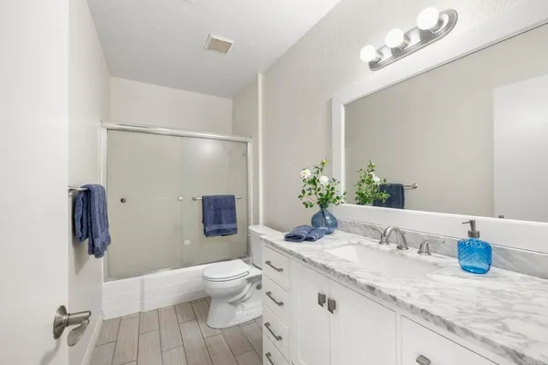 a bathroom with a granite countertop sink a toilet and shower