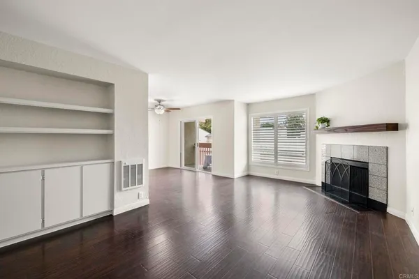 an empty room with wooden floor fireplace and windows