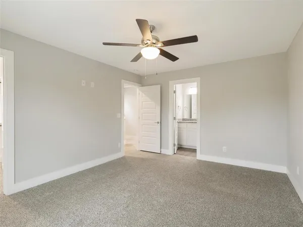 a view of an empty room and window with a ceiling fan
