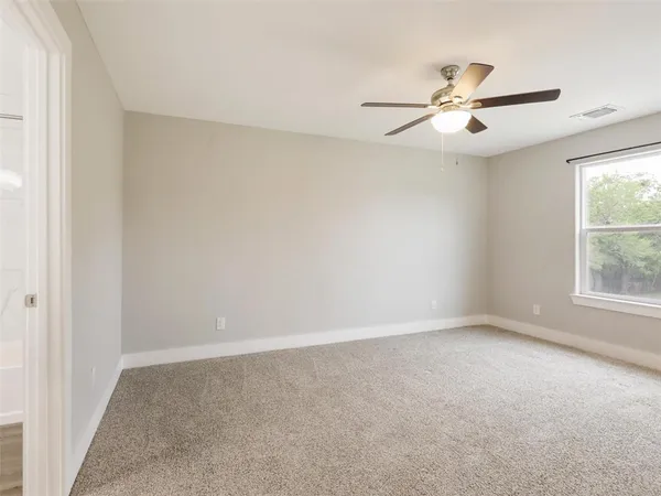 an empty room with windows and fan