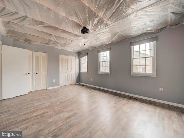 a view of an empty room with wooden floor and windows