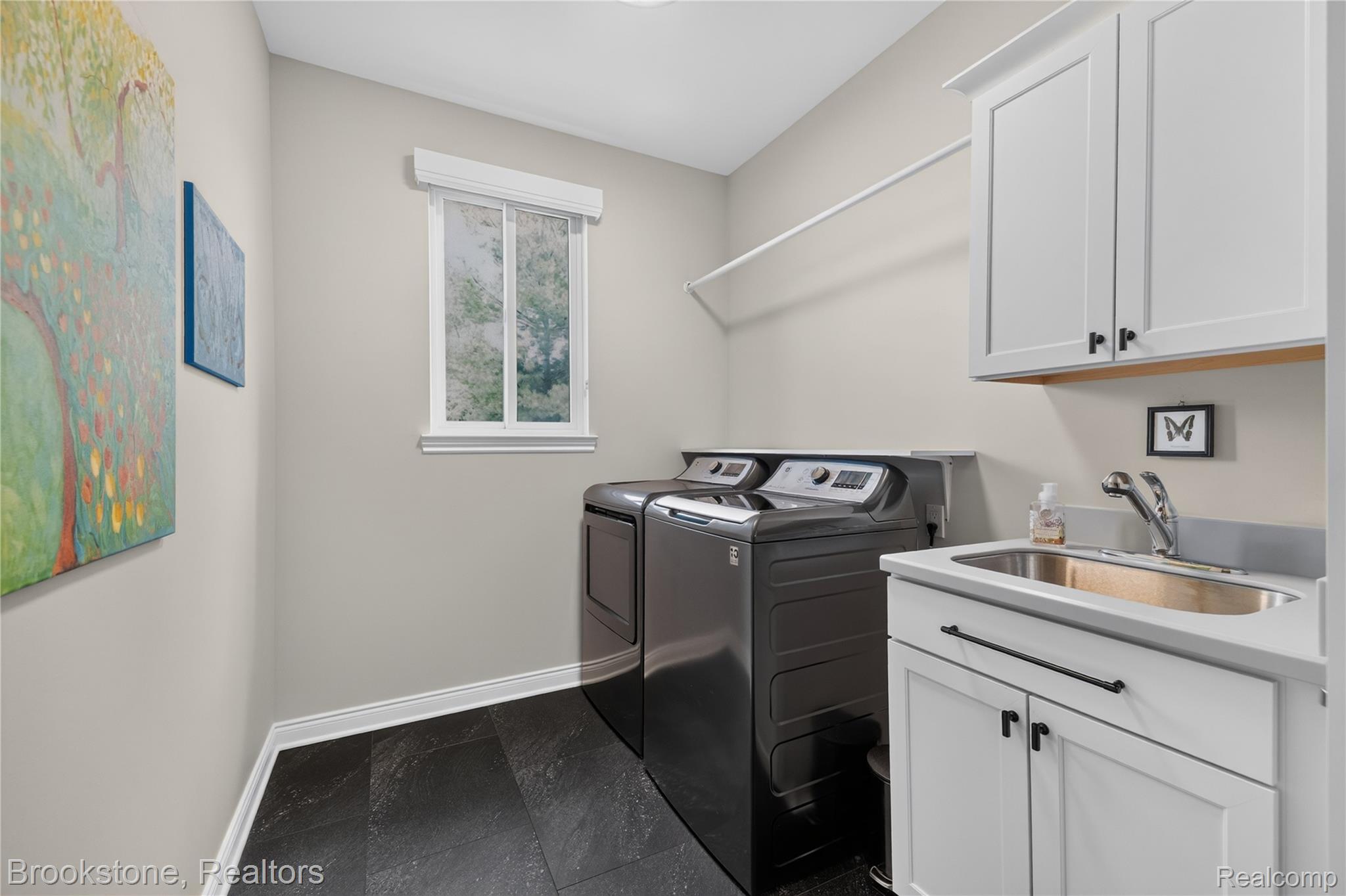 2167 Sanctuary Court Rochester, MI 48309 - Photo 13 of 68 Laundry room featuring dark wood-finish flooring, light grey walls, and a white window with exterior greenery visible