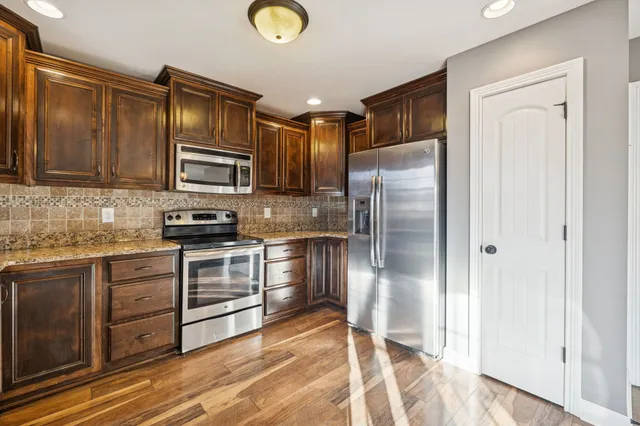 a kitchen with granite countertop a refrigerator stove top oven and sink