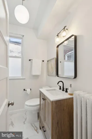 a bathroom with a toilet a sink a mirror and a window