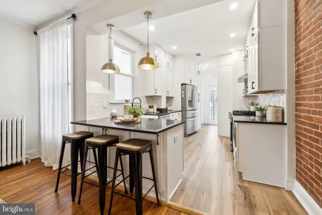a kitchen with stainless steel appliances granite countertop table chairs and a wooden floor