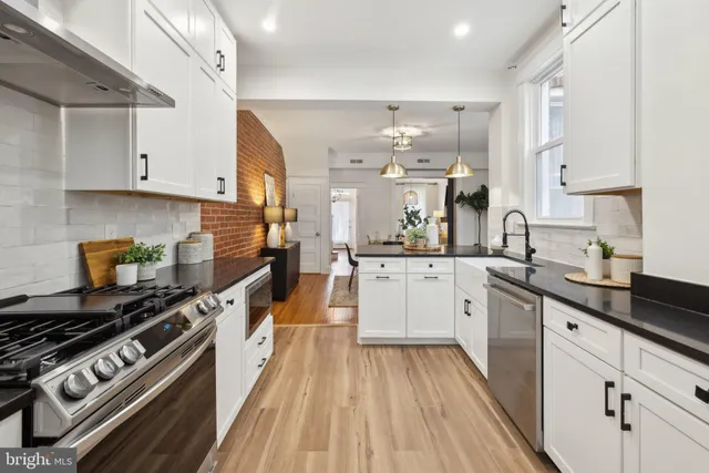 a kitchen with stainless steel appliances a stove a sink dishwasher and white cabinets with wooden floor