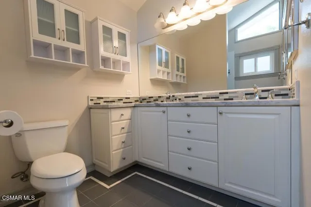 a bathroom with a granite countertop toilet sink and mirror