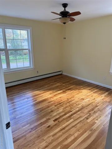 an empty room with wooden floor fan and windows