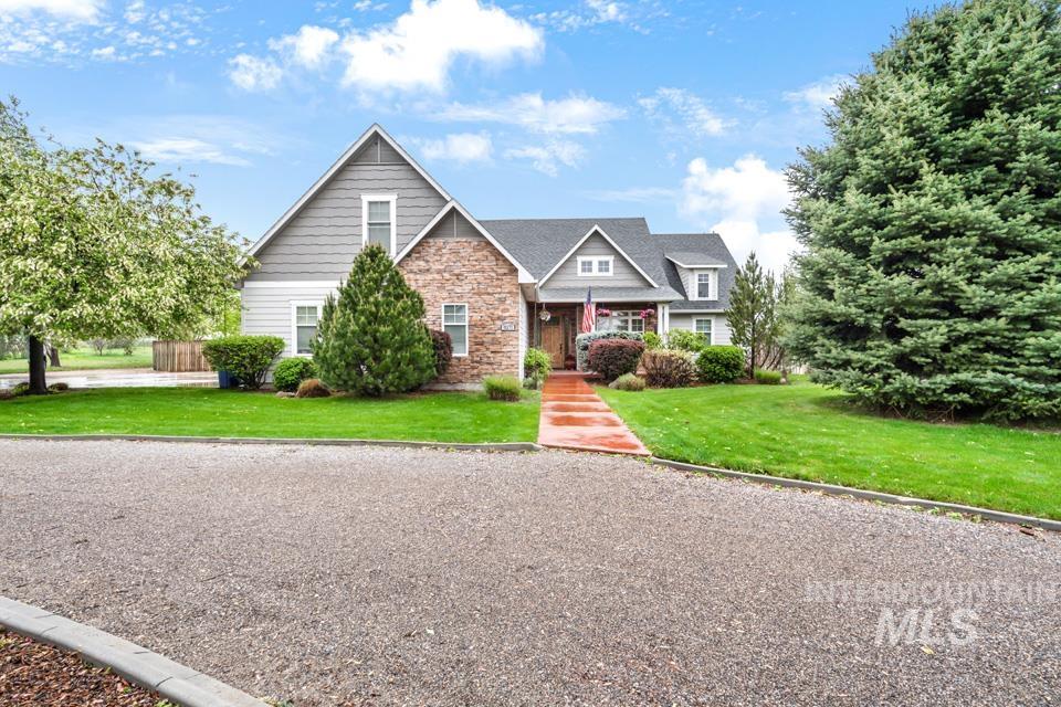 8271 Washoe Road Fruitland, ID 83619 - Photo 2 of 29 Front exterior featuring a gravel driveway, mature trees, and a red-toned walkway leading to the entrance