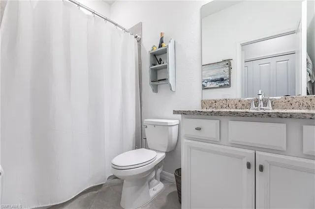a bathroom with a granite countertop toilet sink and mirror