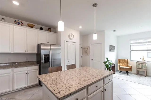 a kitchen with stainless steel appliances kitchen island granite countertop a refrigerator a sink dishwasher and white cabinets with wooden floor