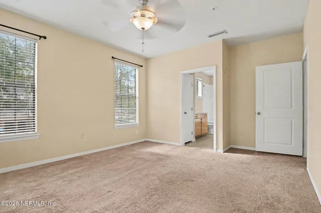 an empty room with a chandelier fan and windows