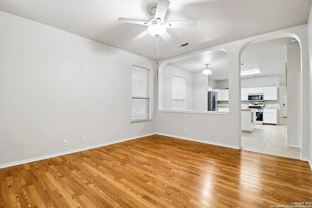 a view of an empty room with wooden floor and a window