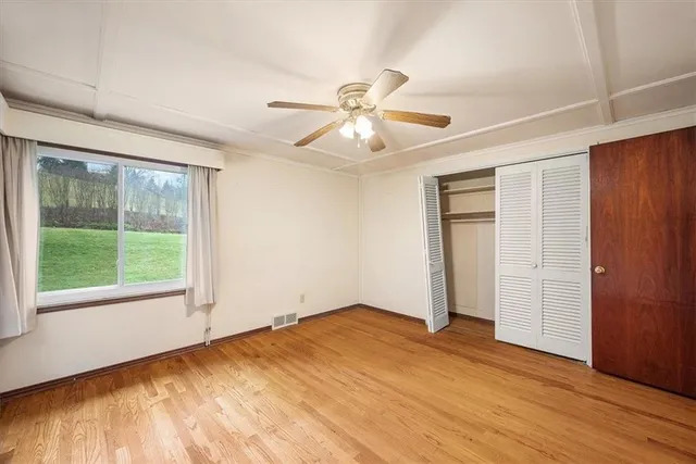 a view of empty room with wooden floor and fan