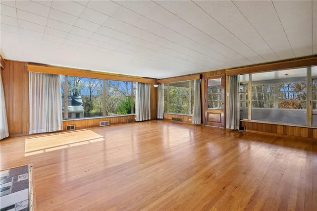 a view of empty room with wooden floor and floor to ceiling window