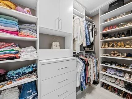 a view of walk in closet with clothes and shoes